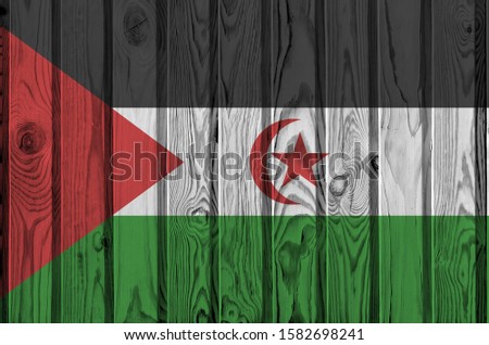 Western Sahara flag depicted in bright paint colors on old wooden wall. Textured banner on rough background