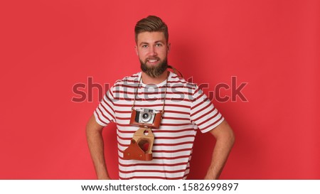 Young man with old fashion came son red background.