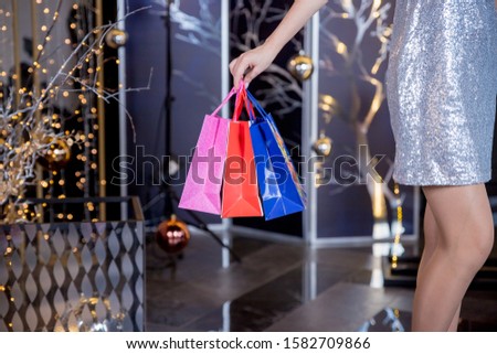 Christmas Shopping. Elegant woman in silver dress In Shopping Mall. Shopping Bags. Holidays and New Year Sales.Woman holding shopping bags making gift in christmas time. Big sale. Marketing and