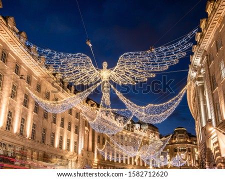 Big angel shape decorations outdoors on Regent Street illuminated by Christmas lights in winter holiday season in London, UK