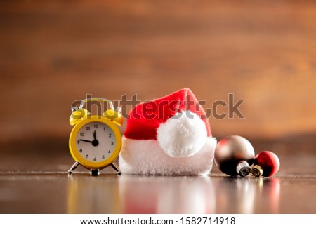 Santa Claus hat and alarm clock on wooden table and background