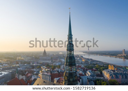 Aerial view photo from flying drone panoramic  to St. Peter's Church and the Old Town on the background of the Daugava River and downtown on a beautiful early morning sunrise (series)
