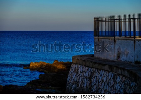 A rock wall near the sea with clear sky in the background