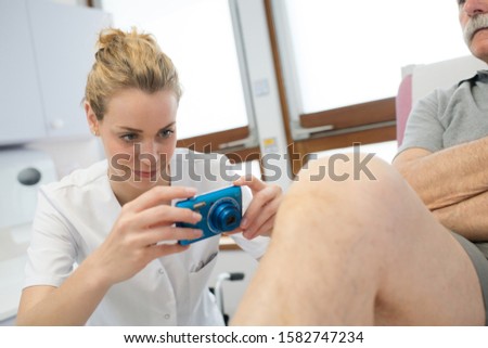 female doctor taking a picture of an injured knee