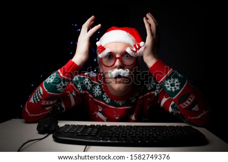 young guy plays on a computer in the New Year at night, a lonely student gamer at Christmas sits near a computer