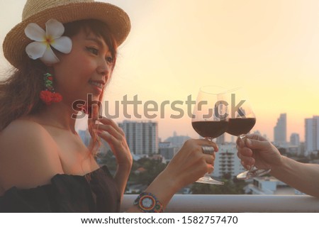 Attractive young asian woman toasting red wine glass on terrace, vintage style