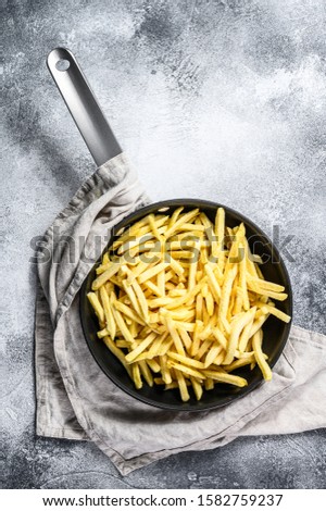 Frozen French fries in a frying pan. Gray background. Top view. Space for text