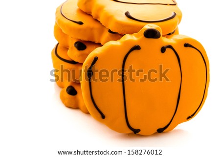 Sugar cookies with orange icing shaped like a pumpkin.