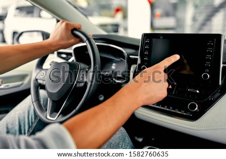 Cropped image hand of man using navigation system or dashboard while driving a car.