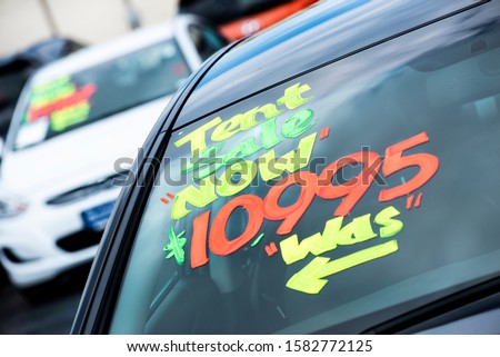 close up of car sale sign price painted on car windows at automobile dealership, transportation, sales, automobile showroom, slumping car sales, bad economy, special deals, 