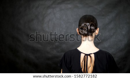 slender brunette girl with elegant hairstyle on a black background.
