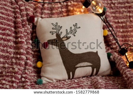 sofa cushion with a picture of a deer on a red and white plaid with a garland