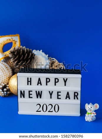 Happy New Year 2020 text on light box with little toy rat and Christmas composition on blue background