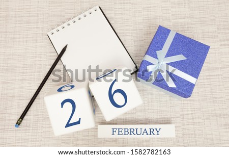 Calendar with trendy blue text and numbers for February 26 and a gift in a box.