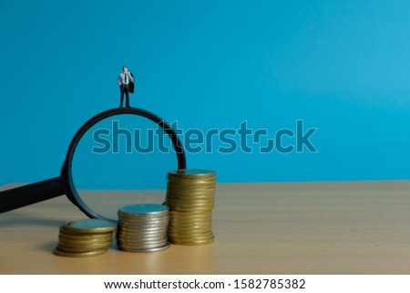 Miniature people concept - a businessman standing on magnifier glass, searching for financial solution / strategy