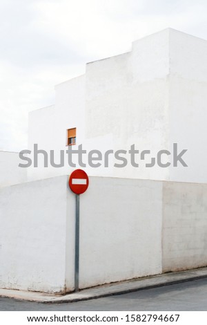 Street stop sign placed on minimalistic whitewashed building background.