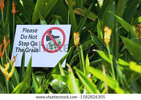 Sign board on the park lawn, asking not to pick up the flowers and please do not step in the grass.