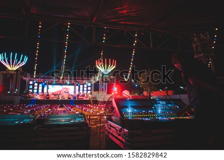 DJ male mixing sound equipment, track in nightclub, party - view of a summer night club outside the disco - focus on soft hands - fun, youth, entertainment and festival ideas
