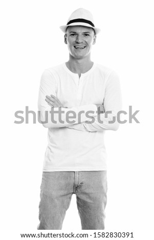 Studio shot of young happy man smiling and standing with arms crossed