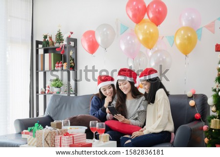 Asian young women enjoy to see a picture in smartphone at Christmas party.