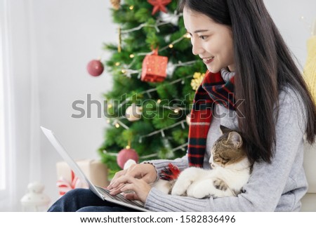 Asian beautiful woman with her cute cat  shopping online by laptop on Christmas Day.
