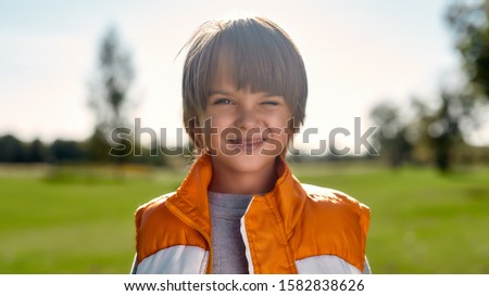 Having fun. Portrait of a cute smiling boy looking at camera while standing in the middle of park on a sunny day. Children. Nature concept. Family day