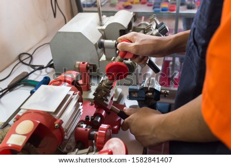 Locksmith in workshop makes new key. Professional making key in locksmith. Machine production of duplicate metal key.