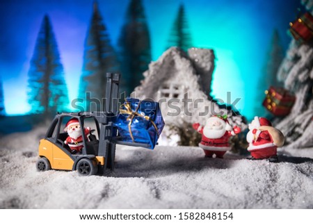 Miniature Gift Box by Forklift Machine on snow ,Determined Image for Christmas Holiday and Happy New Year Gift Celebration concept. Empty space for text
