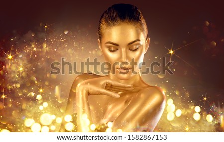 Golden sparkles skin, Woman face portrait closeup. Model girl with holiday golden Glamour shiny professional make up. Gold jewellery, jewelry, accessories. Beauty gold metallic body, fashion Xmas art. Royalty-Free Stock Photo #1582867153