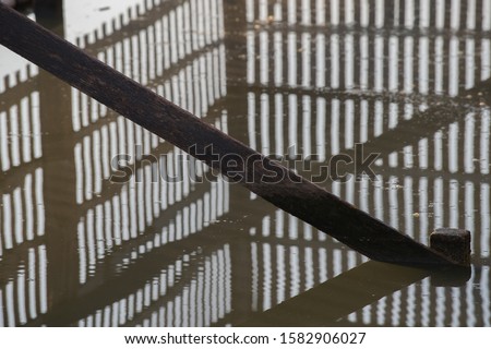 The shadow of a wooden fence reflected in the water
