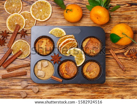 Fresh baked homemade citrus (orange, Mandarin) cakes muffins with brown sugar, cinnamon and star anise in black teflon baking dish over on wooden table. Selective focus, Top view