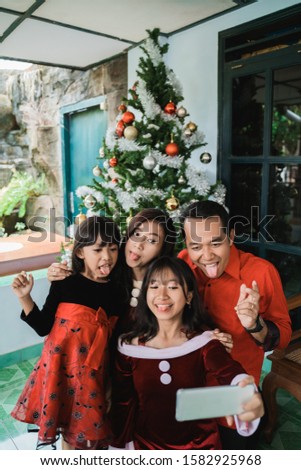 family selfie on christmas day. asian people take picture using mobile phone