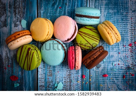 Assorted/ Colorful Macaroons Beautifully Arranged on top of a Blue Wooden Table Decorated with Flowers