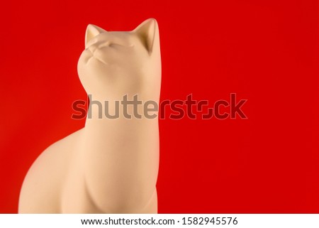 White cat figurine on a red background