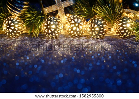 Christmas gold lighting on blue glitter table with tree and decoration. Happy New Year's card