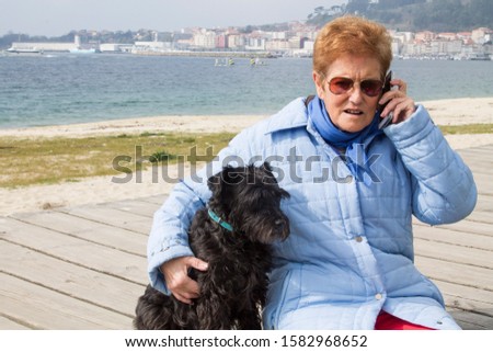 senior woman with her dog talking with mobile phone