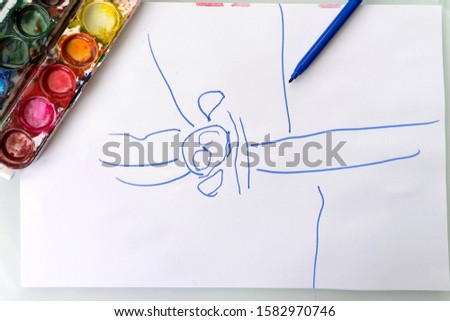 children's drawing. on a white sheet is a little man painted with a blue felt-tip pen. next to it is a set of watercolor paints and an open blue felt-tip pen. creativity of children of three years
