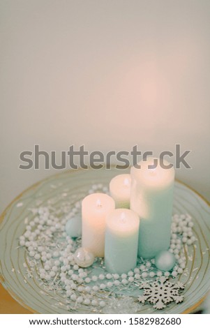 in a blue plate pearls, snowflakes and advent candles burn