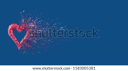 Glitter heart dissolving into pieces on classic blue background. Valentines day, broken heart and love emergence concept. Horizontal wide screen banner format