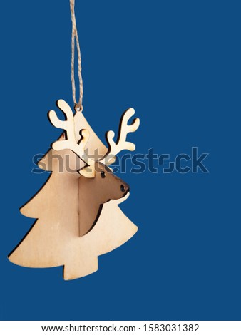 The new color trend of 2020 year - classic blue. Christmas wood toy in the shape of a Santa Deer head with big horns and Christmas trees on a blue classic background