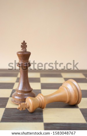 Two kings over a chess board on a beige background. Win and loose concept