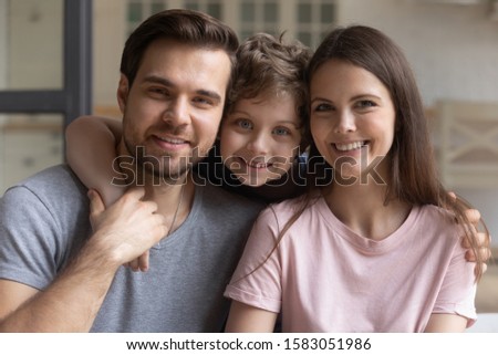 Head shot portrait happy beautiful family dad mom and little son look at camera, child boy smiling embracing mother and father posing with parents enjoy time together, capture moment for album concept Royalty-Free Stock Photo #1583051986
