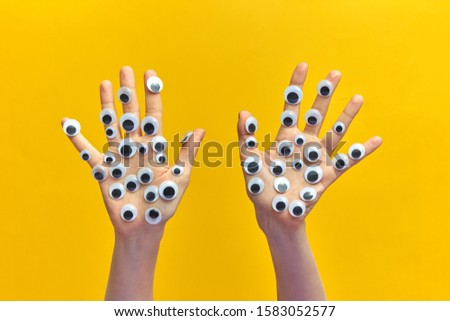 Creative composition from woman hands with plastic eyes on an yellow background, copy space. Sign language concept.