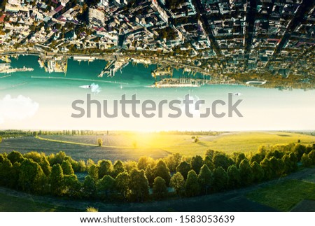 Fantastic surreal terrain of natural landscape and upside down sityscape with sea coastline. Concept of antigravity. Royalty-Free Stock Photo #1583053639