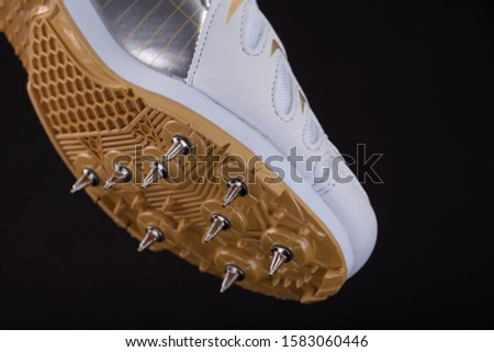 Fragment of a white sneaker with spikes on a black background. Sport shoes