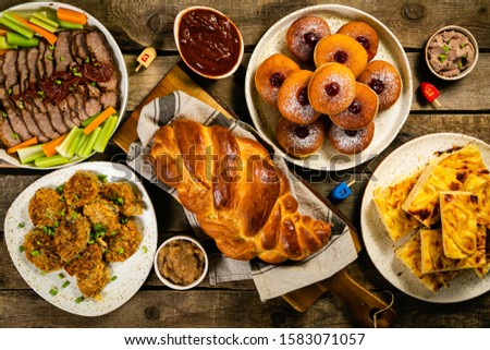 Selection of traditional hanukkah food for festive dinner - Potato Latkes, Applesauce, Challah, Beef Brisket, Sufganiot, Noodle Kugel, Julienned Vegetables