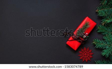 Christmas still life. Gift box with red decoration against a dark background. Luxury New Year gift. Christmas gift. Christmas background with gift box. Christmastime celebration.