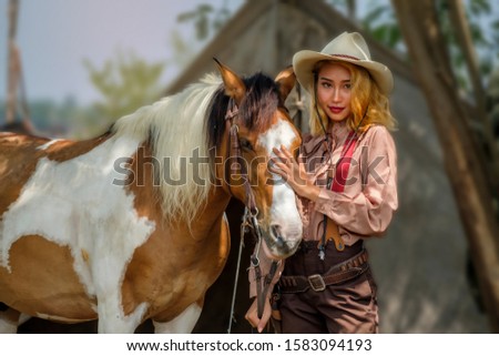 A young cowgirl stand bonding with her horse in cowboys costume, looking at camera