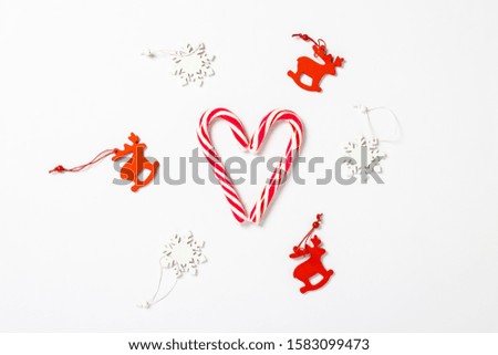 Candy caramel cane in the form of hearts and decorations on a white background. Concept Christmas, New Year, minimalism. Flat lay, top view
