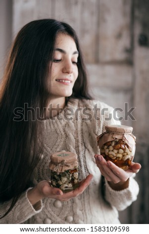 Stock Photo -  Beautiful girl a girl with jars in which honey and nuts